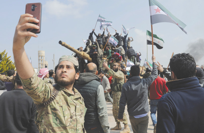 Un combattant rebelle syrien soutenu par la Turquie prend une photo lors d'une manifestation contre l'accord sur des patrouilles conjointes russes et turques sur l'autoroute M4 dans la province syrienne d'Idlib l'année dernière.  (crédit photo : REUTERS/KHALIL ASHAWI)