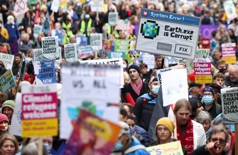  Demonstrators hold signs as they participate in a protest, as the UN Climate Change Conference (COP26) takes place, in London, Britain, November 6, 2021.  (photo credit: REUTERS/HENRY NICHOLLS)