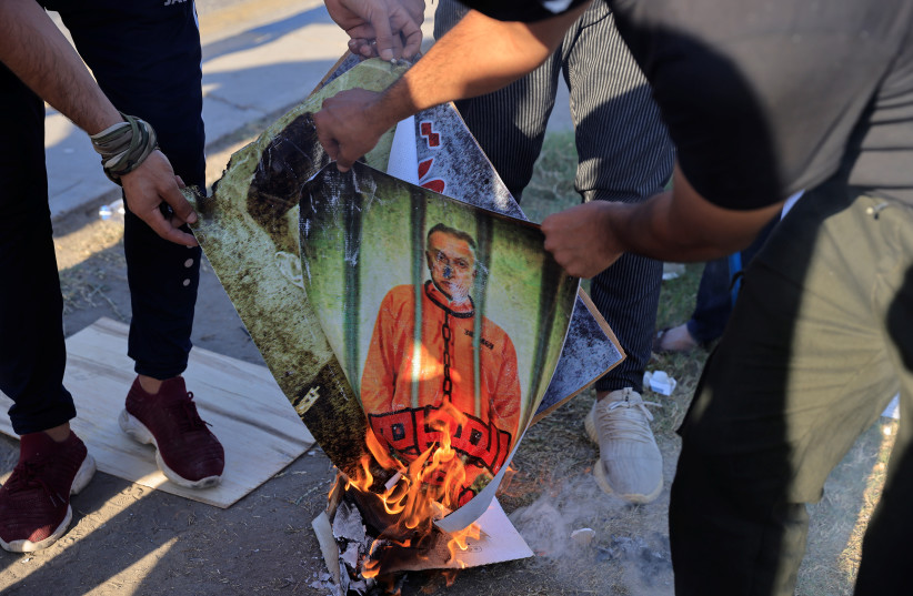  Supporters of Iraqi Shiite armed groups burn portraits of Prime Minister Mustafa al-Kadhemi and Iraq security officials during a protest against the election results near the one of the fortified Green Zone entrances in Baghdad, Iraq, November 6, 2021.  (credit: REUTERS/THAIER AL-SUDANI)
