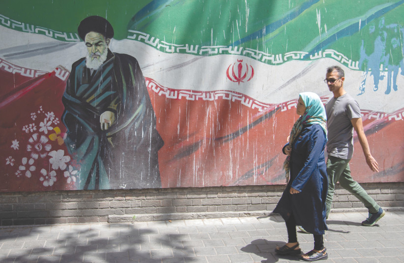  PEOPLE PASS a mural of Iran's late leader Ayatollah Ruhollah Khomeini in Tehran (photo credit: NAZANIN TABATABAEE/WANA VIA REUTERS)