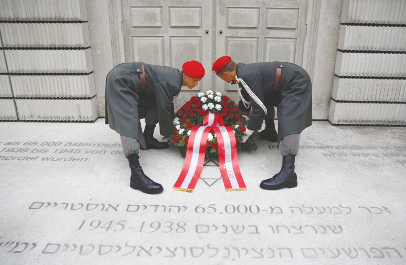  MEMBERS OF the Austrian Armed Forces adjust a wreath during a ceremony marking the 80th anniversary of Kristallnacht in front of the Holocaust Memorial in Vienna in 2018. (photo credit: Leonhard Foeger/Reuters)