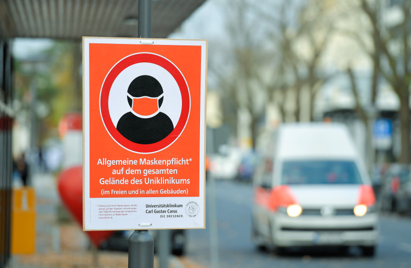  A placard, which reads: "Mandatory use of masks in the whole area inside and outside the buildings", is seen in the University Hospital in Dresden, Germany, November 8, 2021.  (photo credit: REUTERS/MATTHIAS RIETSCHEL)