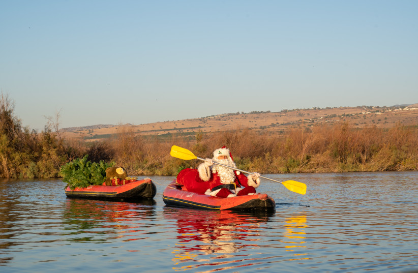  Santa Claus kayaks on the Jordan river with presents and a Christmas tree. (credit: OMRI MESIKA, ROEE PERETZ)