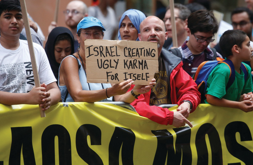  An anti-Israel protester holds up a sign during a demonstration in Times Square in New York City. (photo credit: CARLO ALLEGRI/REUTERS)