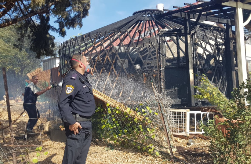  An Israel Police officer is seen looking at a damaged house in the Gita village fire on November 13, 2021 (credit: FIRE AND RESCUE SERVICE)