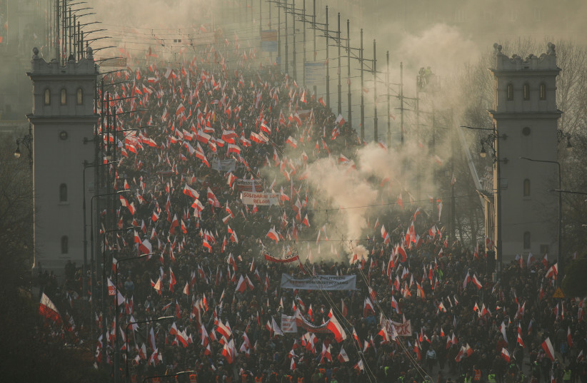  Demonstrators carry Polish flags during a march marking the National Independence Day in Warsaw, Poland November 11, 2021. (photo credit: DAWID ZUCHOWIGZ/AGENCA WYBORCZA.PL VIA REUTERS)