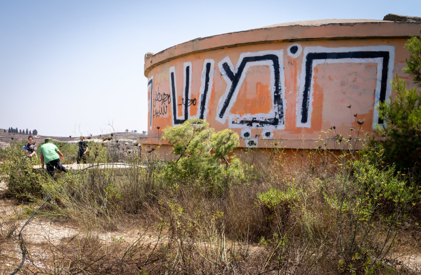  Visitors walk by the water tower on the ruins of the evacuated settlement of Homesh on August 27, 2019. Homesh was one of four West Bank settlements that Israel evacuated during the disengagement. (photo credit: HILLEL MAEIR/FLASH90)
