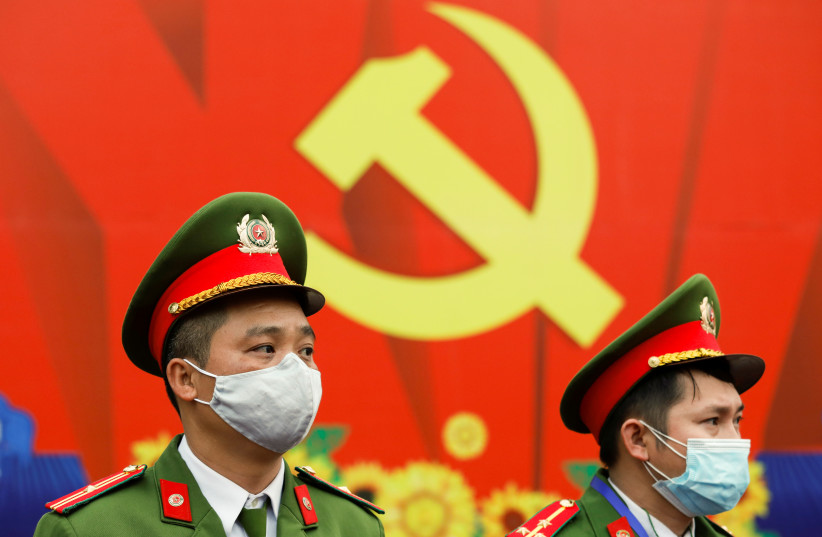  Police officers, wearing protective masks, stand guard in front of a communist logo at the National Convention Center, the venue for the 13th National Congress of the Communist Party of Vietnam during the coronavirus disease (COVID-19) outbreak in Hanoi, Vietnam January 28, 2021 (credit: REUTERS/KHAM)