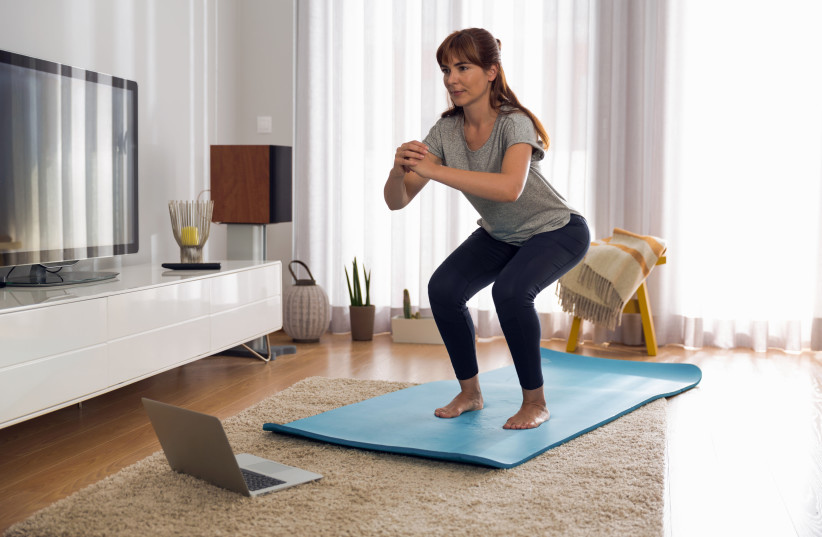 Woman doing exercise at home (photo credit: INGIMAGE)