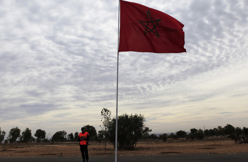 A police officer stands near a Moroccan national flag near the main stadium during preparations for the FIFA Club World Cup in Agadir, December 10, 2013. (photo credit: REUTERS/AMR ABDALLAH DALSH)