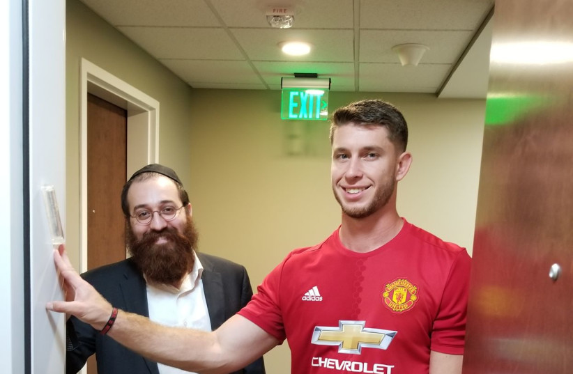  Joseph with Rabbi Yossi Friedman of the Chabad of Downtown Cleveland in 2018, standing by the mezuzah that Friedman helped Joseph put up outside his apartment.  (credit: GLEN JOSEPH)