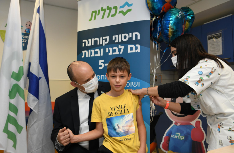 Prime Minister Naftali Bennett is seen accompanying his nine-year-old son get vaccinated against COVID-19 as Israel rolls out vaccinations for children aged 5-11, on November 23, 2021. (photo credit: AMOS BEN GERSHOM/GPO)