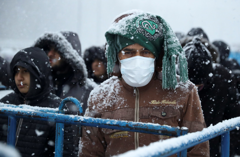  Migrants gather at a transport and logistics centre during snowfall, near the Belarusian-Polish border, in the Grodno region, Belarus. (photo credit: KACPER PEMPEL/REUTERS)