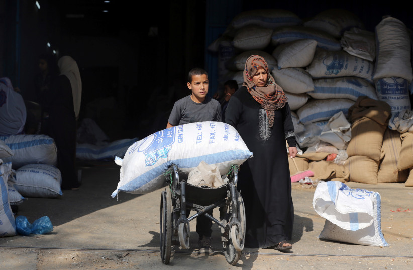  A Palestinian boy uses a wheelchair to transport a bag of peanuts as he helps his mother who makes a living by peeling peanuts for a factory, in Rafah in the southern Gaza Strip January 22, 2019 (photo credit: REUTERS/IBRAHEEM ABU MUSTAFA)