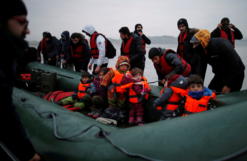  A group of more than 40 migrants with children get on an inflatable dinghy, as they leave the coast of northern France to cross the English Channel, near Wimereux, France, November 24, 2021 (photo credit: REUTERS/GONZALO FUENTES)
