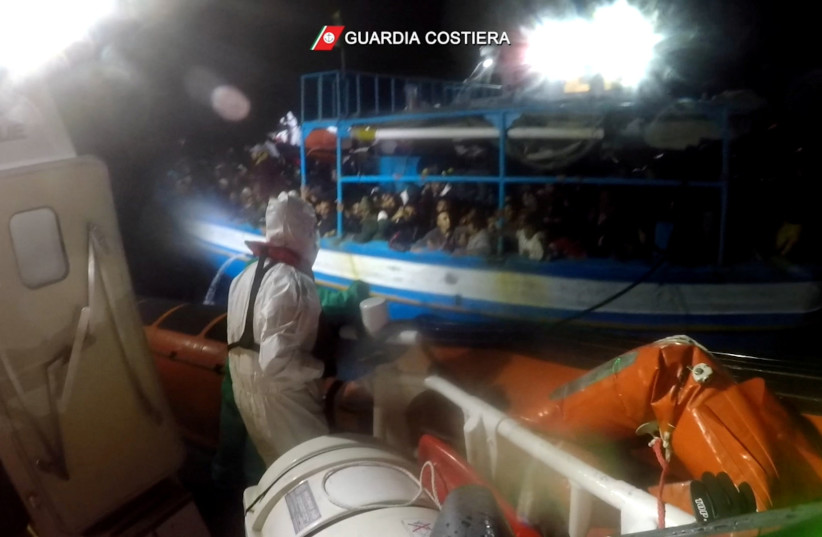  Italian coastguard members throw a rope to a boat in distress carrying migrants, during a rescue operation in the Mediterranean Sea, in this still image taken from a video, November 25, 2021 (photo credit: ITALIAN COAST GUARD/HANDOUT VIA REUTERS)