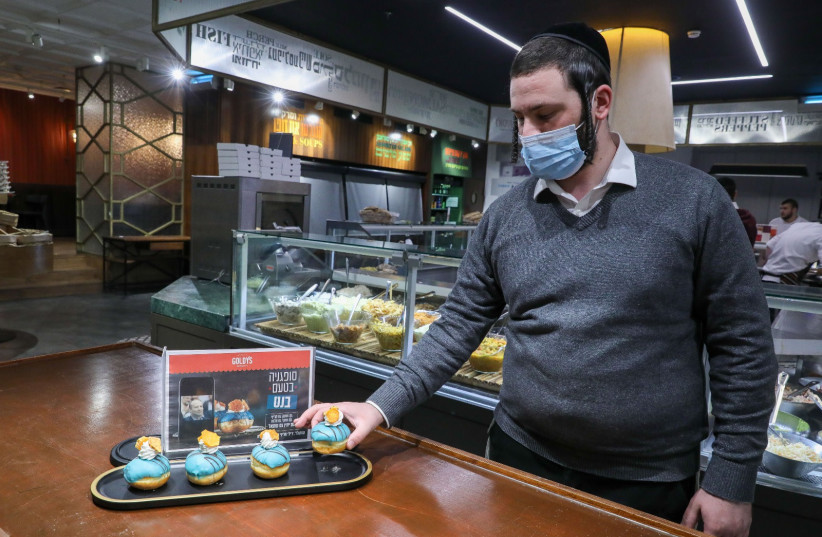  A man is seen picking up a Bennett-flavored donut at Goldy's bakery in Jerusalem. (credit: MARC ISRAEL SELLEM/THE JERUSALEM POST)