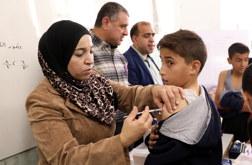  Children aged 12-15 receive their first first dose of Covid-19 vaccine, at at their school in the West Bank city of Hebron, November 24, 2021. (credit: WISAM HASHLAMOUN/FLASH90)