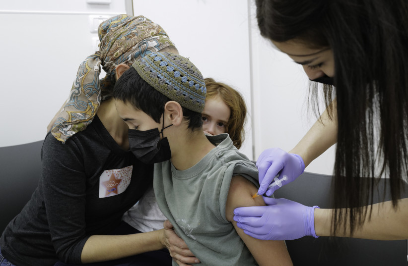  Children aged 5-11 receive their first first dose of Covid-19 vaccine, at Maccabi vaccination center in Katsrin, Golan Heights, on November 24, 2021.  (photo credit: MICHAEL GILADI/FLASH90)