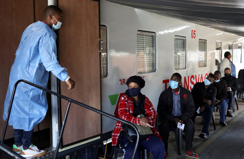   A health worker talks to people as they wait to register next to the Transvaco coronavirus disease (COVID-19) vaccine train, after South Africa's rail company Transnet turned the train into a COVID-19 vaccination center on rails to help the government speed up its vaccine rollout in the country (credit: REUTERS/ SIPHIWE SIBEKO)