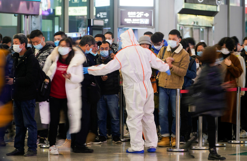  A security guard blocks an exit as he directs people to scan a QR code to track their health status at Shanghai Hongqiao Railway Station, following new cases of the coronavirus disease (COVID-19), in Shanghai, China, November 25, 2021. (photo credit: REUTERS/ALY SONG)