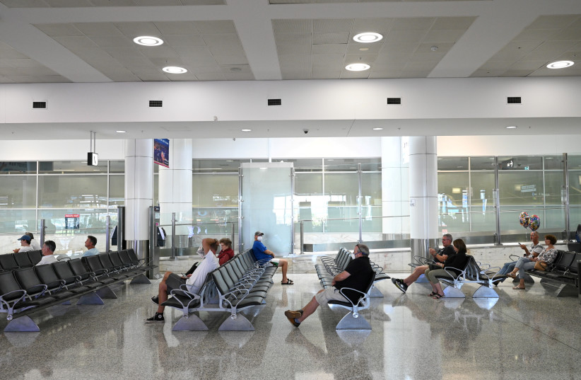  People sit in the arrivals section of the international terminal of Kingsford Smith International Airport the morning after Australia implemented an entry ban on non-citizens and non-residents intended to curb the spread of the coronavirus disease (COVID-19) in Sydney, Australia, March 21, 2020. (photo credit: REUTERS/LOREN ELLIOTT)
