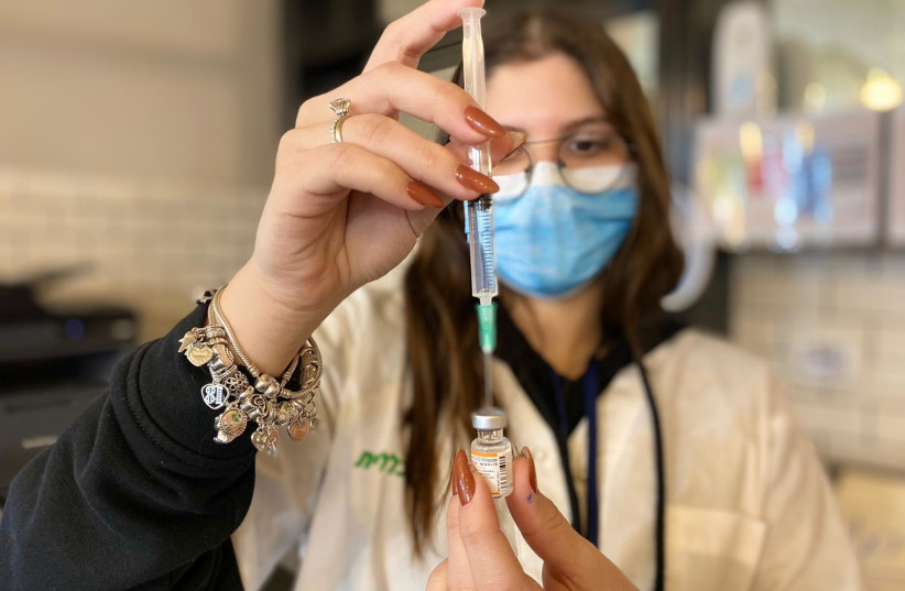A Clalit health worker fills a syringe with the COVID-19 vaccine at Cinema City in Jerusalem. (photo credit: CLALIT HEALTH SERVICES)