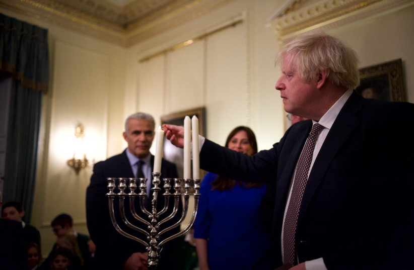  UK Prime Minister Boris Johnson lighting Hannukah candles as Yair Lapid looks on (photo credit: STUART MITCHELL)