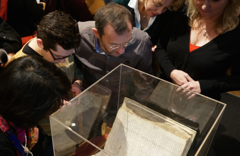  Attendees at an Amsterdam symposium on whether to lift the ancient order of excommunication against the philosopher Baruch Spinoza examining a copy of the original writ against him, Dec. 6, 2015.  (credit: CNAAN LIPHSHIZ/JTA)