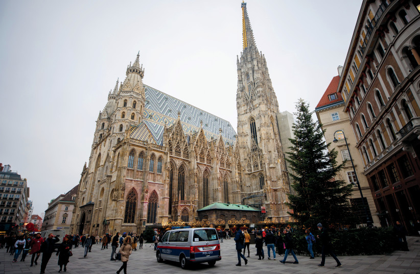  A police car stands guard as pedestrians pass St. Stephen’s Cathedral, after the Austrian government placed roughly two million people who are not fully vaccinated against corona on lockdown in Vienna on November 15, 2021. (credit: LISI NIESNER)