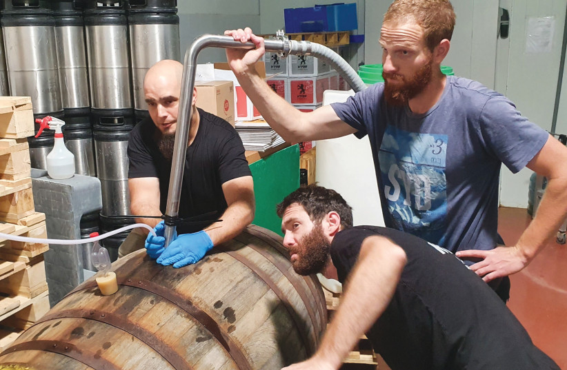  Ory Sofer and the Shapiro brewing team transfer a sour beer from the barrel to a tank before bottling (credit: Courtesy)