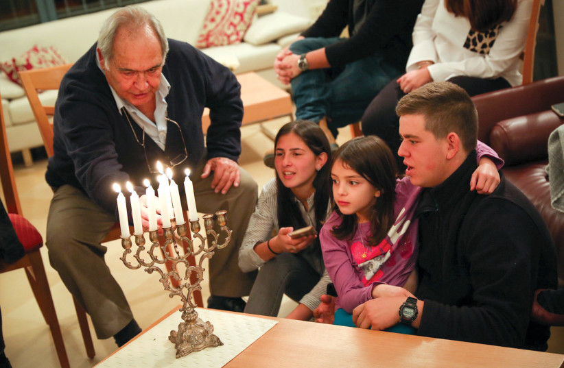 A family lighting Hanukkah candles: The holidays can also evoke somber challenges. (photo credit: NATI SHOHAT/FLASH90)