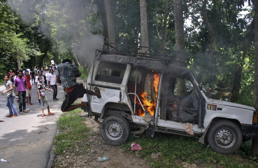  A demonstrator kicks a vehicle that was set on fire during a protest at Golaghat district in the northeastern Indian state of Assam August 20, 2014. (photo credit: REUTERS/STRINGER)