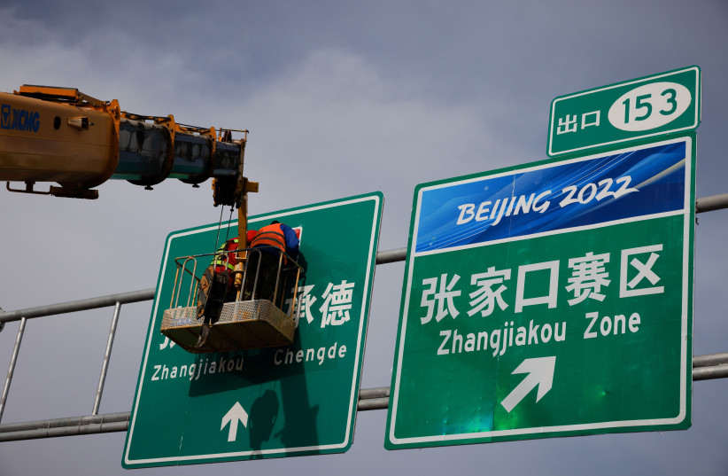 Men work on a traffic sign on a highway leading to venues of the Beijing 2022 Olympics in Zhangjiakou, Hebei province, China, November 19, 2021. (credit: REUTERS/THOMAS PETER)