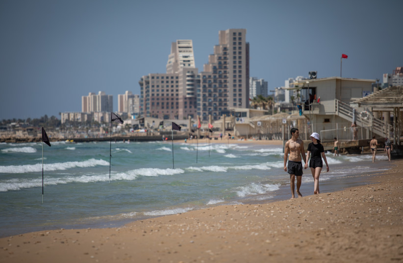 Israelis walk along Dado Beach in Haifa on May 16, 2021. (photo credit: SHIR TOREM/FLASH90)