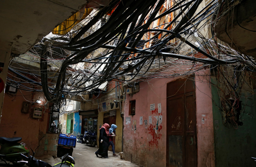  Women walk under electricity cables in Shatila Palestinian refugee camp, as the spread of coronavirus disease (COVID-19) continues, in Beirut suburbs, Lebanon March 30, 2020 (photo credit: MOHAMED AZAKIR/REUTERS)