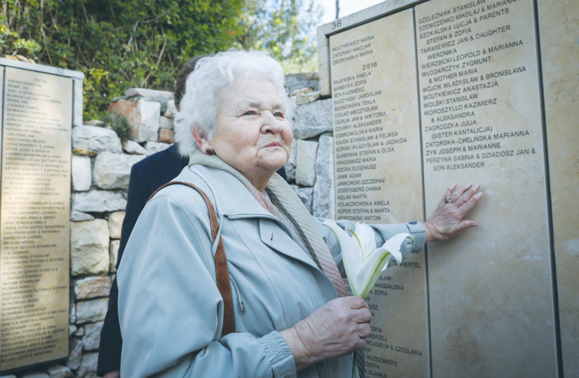  A WOMAN from Poland places her hand near the names of family members honored at Yad Vashem in 2018 as Righteous Among the Nations. (photo credit: NOAM REVKIN FENTON/FLASH90)