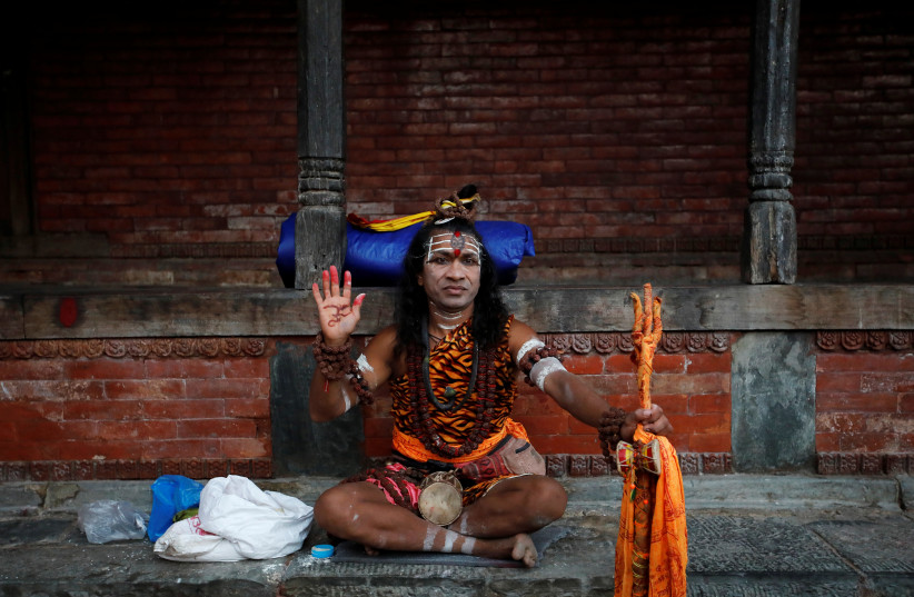A man dressed as Lord Shiva sits at the premises of Pashupatinath Temple during the Teej festival in Kathmandu, Nepal, September 2, 2019. (photo credit: REUTERS/NAVESH CHITRAKAR/FILE PHOTO)