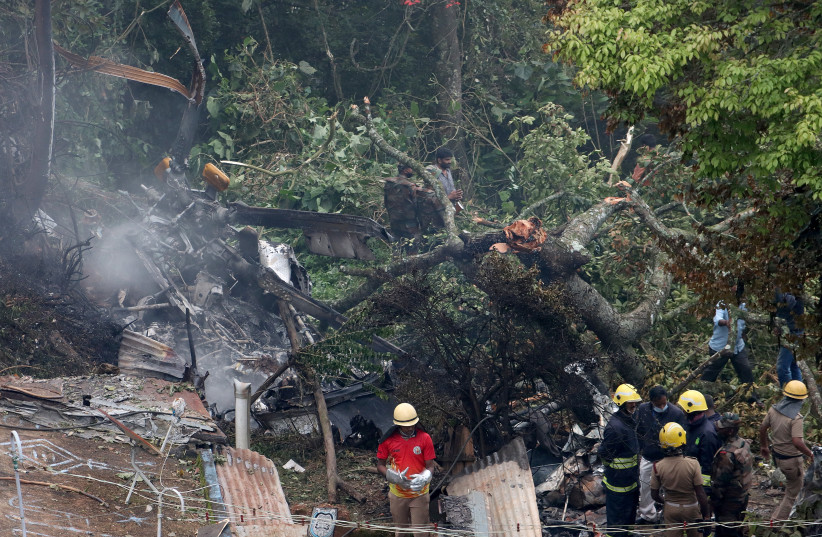  Rescuers stand near the debris of the Russian-made Mi-17V5 helicopter after it crashed near the town of Coonoor (photo credit: REUTERS)