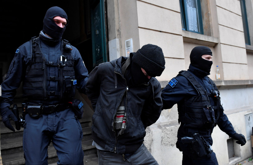 Police detain a suspect during raids in several locations in Dresden, Germany, December 15, 2021. (photo credit: REUTERS/MATTHIAS RIETSCHEL)