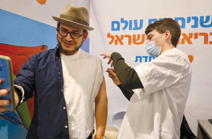  A DOUBLE shot: A man takes a ‘vaxxie’ at a Jerusalem vaccination center.  (photo credit: MARC ISRAEL SELLEM/THE JERUSALEM POST)