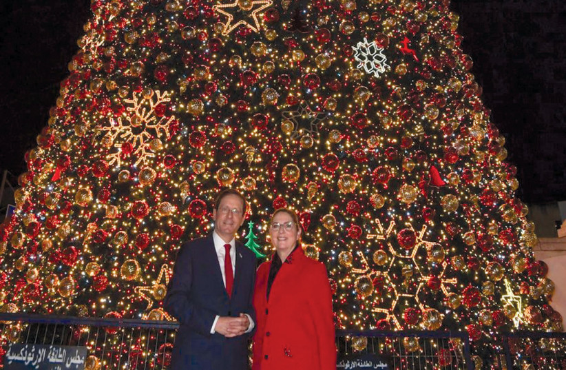  PRESIDENT ISAAC HERZOG and his wife, Michal, pose in front of what is believed to be the biggest Christmas tree in the Middle East during their visit to Nazareth. (credit: KOBI GIDEON/GPO)