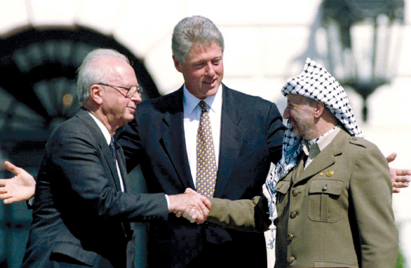  PRIME MINISTER Yitzhak Rabin shakes hands with PLO chairman Yasser Arafat, as US president Bill Clinton looks on at the White House at the signing of the Oslo I Declaration of Principles on September 13, 1993. (photo credit: GARY HERSHORN/REUTERS)