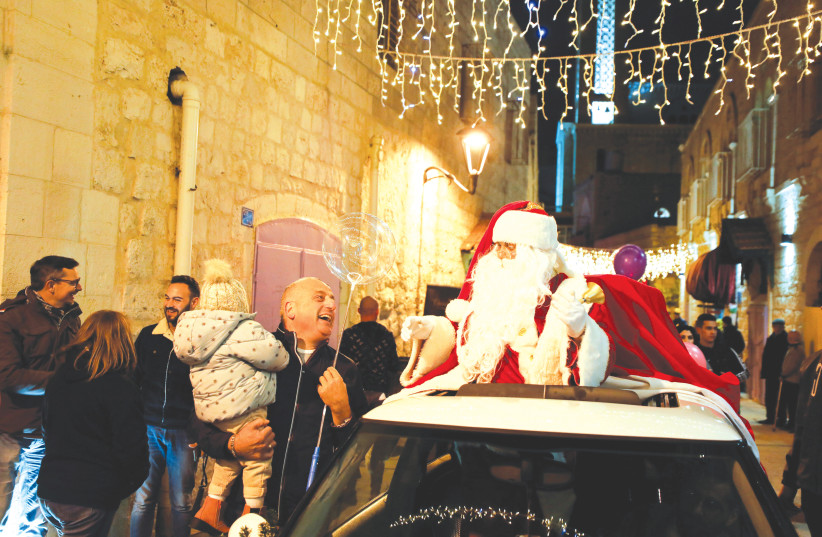  A MAN DRESSED as Santa meets people on a Bethlehem street, earlier this month. (photo credit: REUTERS/MUSSA QAWASMA)