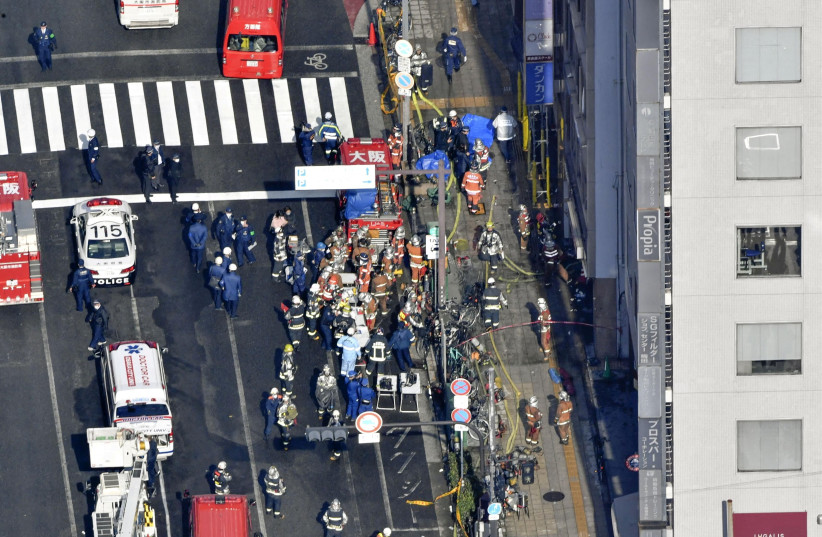  Firetrucks and firefighters are seen in front of a building where a fire broke out in Osaka, western Japan December 17, 2021 in this photo taken by Kyodo. (photo credit: KYODO/VIA REUTERS)