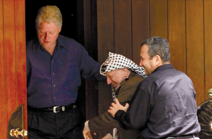 Former Prime Minister Ehud Barak jokingly pushes Palestinian Authority leader Yasser Arafat into a cabin on the grounds of Camp David as then-US president Bill Clinton watches during their summit in July 2000. (photo credit: WIN MCNAMEE/REUTERS)