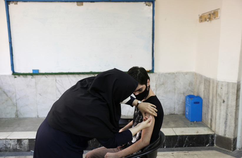  An Iranian teenager receives a dose of a vaccine against the coronavirus disease (COVID-19) at a school in Tehran, Iran October 7, 2021. (photo credit: MAJID ASGARIPOUR/WANA (WEST ASIA NEWS AGENCY) VIA REUTERS)