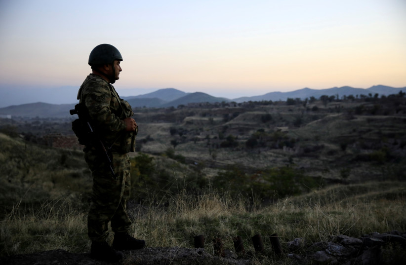 An Azeri soldier inspects the city of Cebrayil, where Azeri forces regained control during the fighting over the breakaway region of Nagorno-Karabakh, Azerbaijan, October 16, 2020. (photo credit: REUTERS/UMIT BEKTAS)