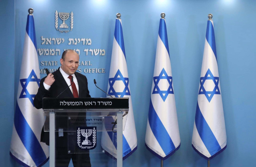   Le Premier ministre Naftali Bennett est vu en train de retirer son masque facial lors d'une conférence de presse spéciale sur COVID-19 à Jérusalem, le 19 décembre 2021. (Crédit : MARC ISRAEL SELLEM/THE JERUSALEM POST)