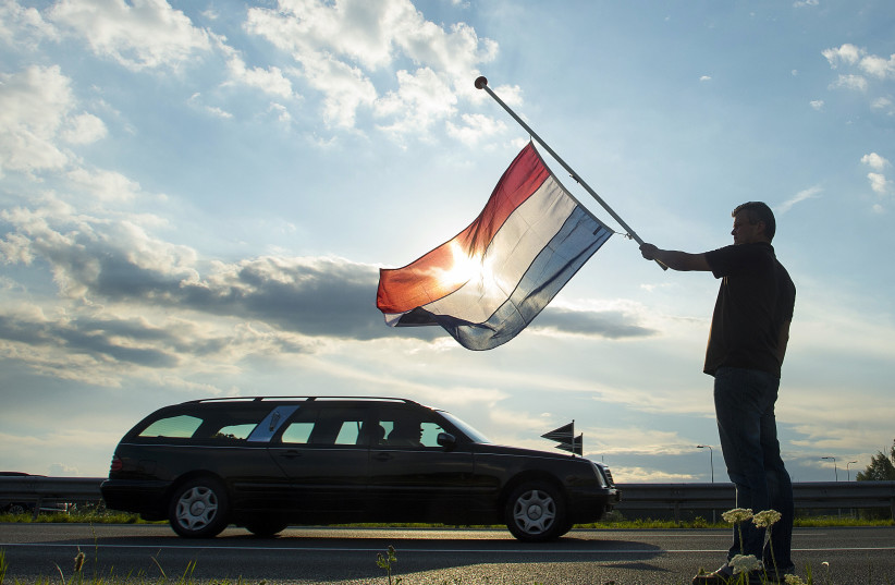  Ronald Visee holds a Netherlands flag flying at half-mast  (photo credit: REUTERS/TOUSSAINT KLUITERS)